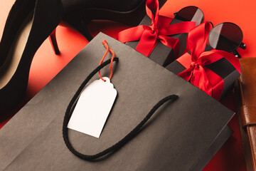 Gift bag, gift boxes, shoes, wallet, sunglasses and copy space over red background
