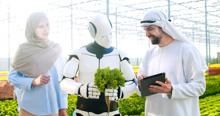 Arabian man in white traditional emirati clothing and woman in hijab discussing with humanoid...