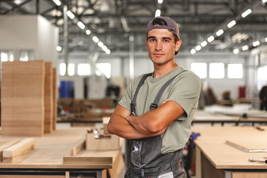 Portrait of young male carpenter standing in the wood workshop