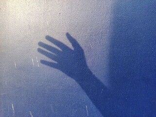 hand silhouette background on blue wall. news illustration concept about asking for help in cases of violence	
