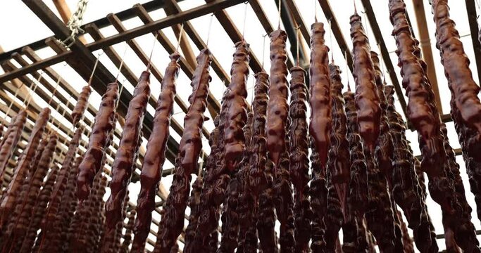 Red-colored Georgian national sweetness hanging on ropes in resort market. Homemade delicacy churchkhela on seaside market low angle shot