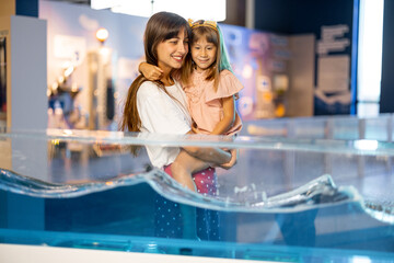Mom with little daughter learn physics interactively on a model that shows physical phenomena while...