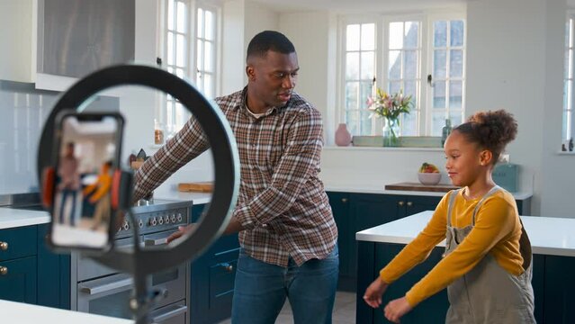 Embarrassed daughter teaching Dad social media flossing dance routine and recording it on mobile phone - shot in slow motion