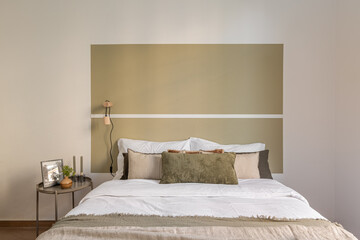 Direct horizontal shot of a double bed in a honeymoon hotel room in beige and olive tones. The...