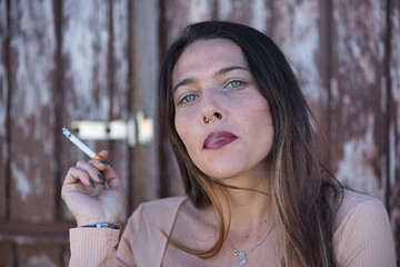 Portrait of a woman, young and attractive, blue eyes, smoking a cigarette and exhaling smoke....