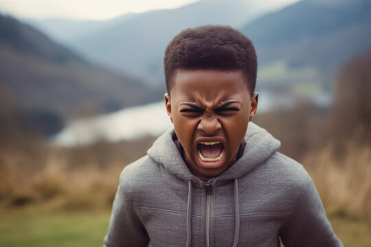 Anger African Boy In A Gray Sweatshirt On Nature Landscape Background