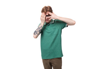 a young modest european man with red hair and a stylish hairstyle is dressed in a green summer t-shirt