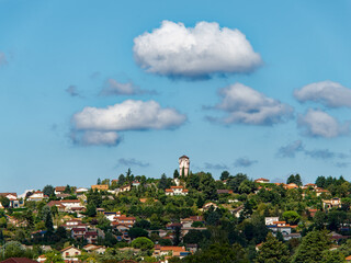 Fototapeta premium View of the city of Communay and its iconic water tower, a sunny day with scattered clouds, France