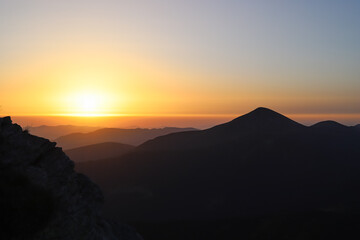 low key dawn in the mountains, black silhouettes of mountains on the background of the sunrise