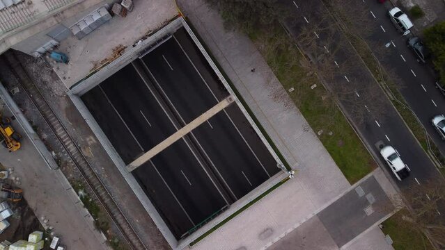 Underground parking under construction, cars passing parallel on a regular road nearby