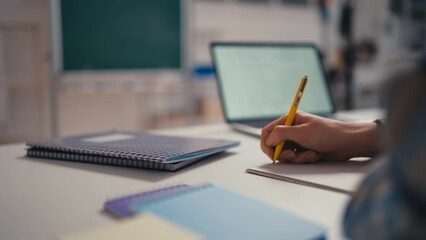 Closeup of a pupil writing in a notebook in the classroom, studying in school - Powered by Adobe