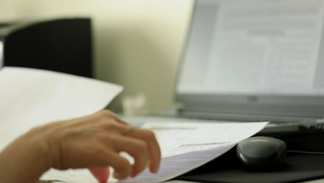 Office worker checking and reviewing individual sheets of paperwork at desk