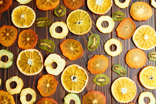 Colorful fruit chips on dark wood table