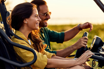Obraz premium A smiling man driving a quad bike and enjoying the adventure with his girlfriend.