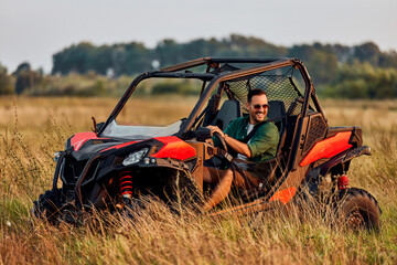 A happy man enjoying an adventure and driving a quad bike off-road.