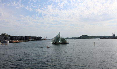 Fototapeta premium City Oslo harbor with monument in the sea in the sunny morning over beautiful big city background, luxury summer adventure, active vacation in Oslofjord, Norwey
