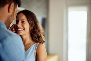 A happy woman looks at her boyfriend with love before kissing him at home.