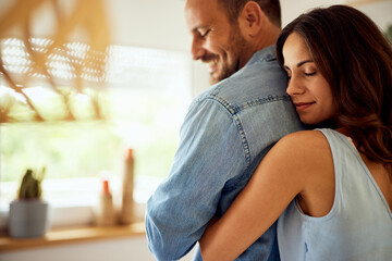 Brunette woman hugging her man from behind, being at home.