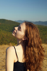 portrait of a happy woman in the mountains, with her hair blown by the wind on a sunny day
