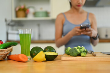 Glass of green smoothie and ingredients on wooden tabletop. Detox, dieting, healthy food concept