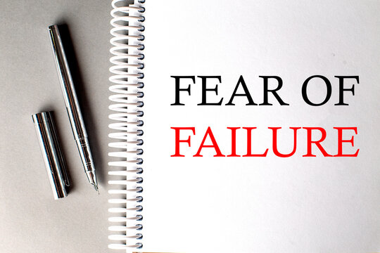 FEAR OF FAILURE text on a notebook with pen on grey background