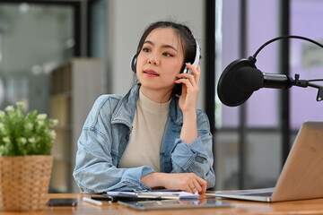 Female host listening to interesting conversation with guest during streaming podcast in studio