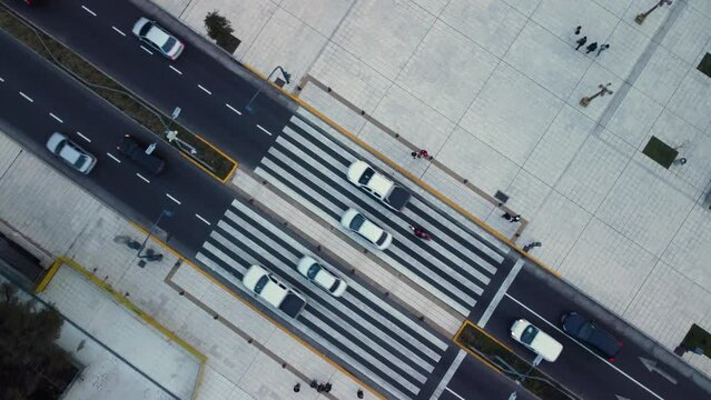 Cars drive along the road and cross a zebra crossing, the drone zooms in and rotates