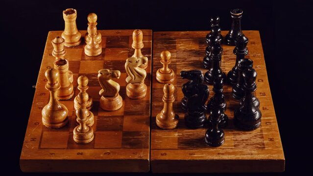 Playing with old chess pieces in the middlegame, stop motion. Retro chess game with a queen gambit opening on a black background