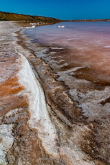 Salt Lake. Self-settling sodium chloride salt on rocks near the shore. Hypersaline water in a drying lake i