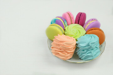 Various desserts. Macaroons, marshmallows and zephyrs in plate on a white background. Traditional...