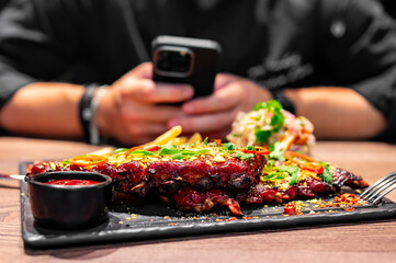 man with phone sit in bar and Pork ribs with french fries and coleslaw salad