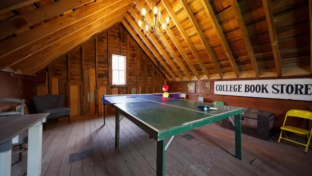 wide push in shot of a vintage gaming room on the upper level of a barn with a ping pong table