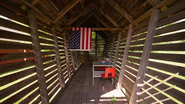 Push in wide shot of an outdoor kids playroom with a table and chairs and an American flag hanging