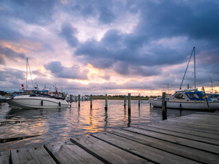 Wooden pier with boats in the evening light with thunderstorm approaching in the distance