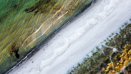 Aerial shot of a sandy beach running diagonally through the image