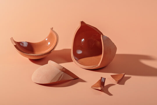 Details of broken ceramic cup on beige background. Macro close up of trendy hard shadows from broken pot, selective focus