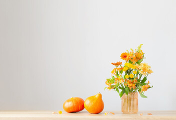 autumn bouquet and orange pumpkins  on wooden shelf on background gray wall