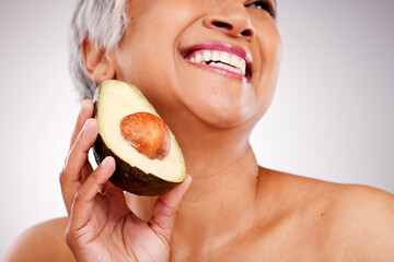 Senior, happy woman and avocado in skincare or natural nutrition against a studio background....