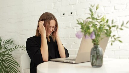 Exhausted frustrated young overworked woman massaging temples after works or studies remote online on laptop. Stressed tired millennial girl suffering from migraine, panic attack, high blood pressure.