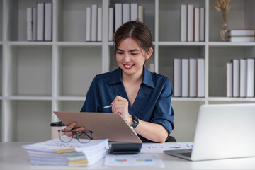 A business woman sits and examines tax documents and inspects corporate operations with a smile on her face.