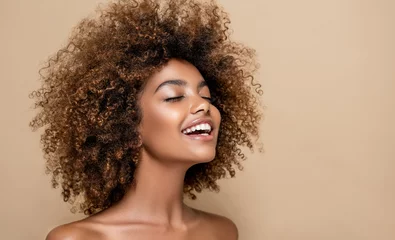 Schilderijen op glas Beautiful black woman . Beauty portrait of african american woman with clean healthy skin on beige background. Smiling beautiful afro girl.Curly black hair . Afro Hairstyle © Sofia Zhuravetc