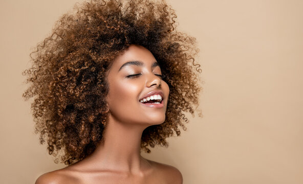 Beautiful black woman . Beauty portrait of african american woman with clean healthy skin on beige background. Smiling beautiful afro girl.Curly black hair . Afro Hairstyle