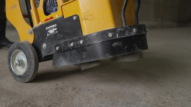  The builder uses machine polishing of the floor surface, smoothing and finishing of hardener or epoxy concrete in a factory. Concrete grinding machine.