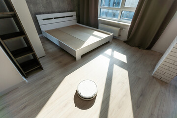 Robotic vacuum cleaner on laminate wood floor in living room