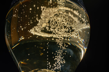 Glass of french sparkling champagne wine with bubbles on dark background, bubbles close up
