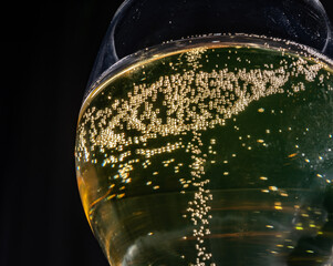 Glass of french sparkling champagne wine with bubbles on dark background, bubbles close up
