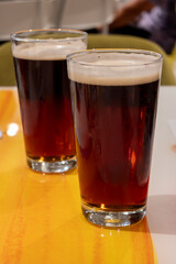Pint glasses of cold fresh british IPA ale and lager beer served in old vintage English pub