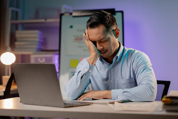 Asian man showing tired and stressed expression in the office, company employee working overtime, working late at night, working overtime of a busy and hard working company employee. Overtime concept.