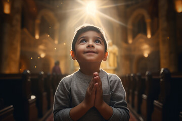 Cute small Latin boy praying in the church and Jesus giving blessing