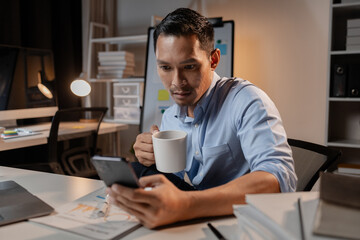 Fototapeta premium Asian businessman uses mobile phone in the office, he is a young and energetic company executive, managing the company to grow and working hard for profit. Start-up company management concepts.